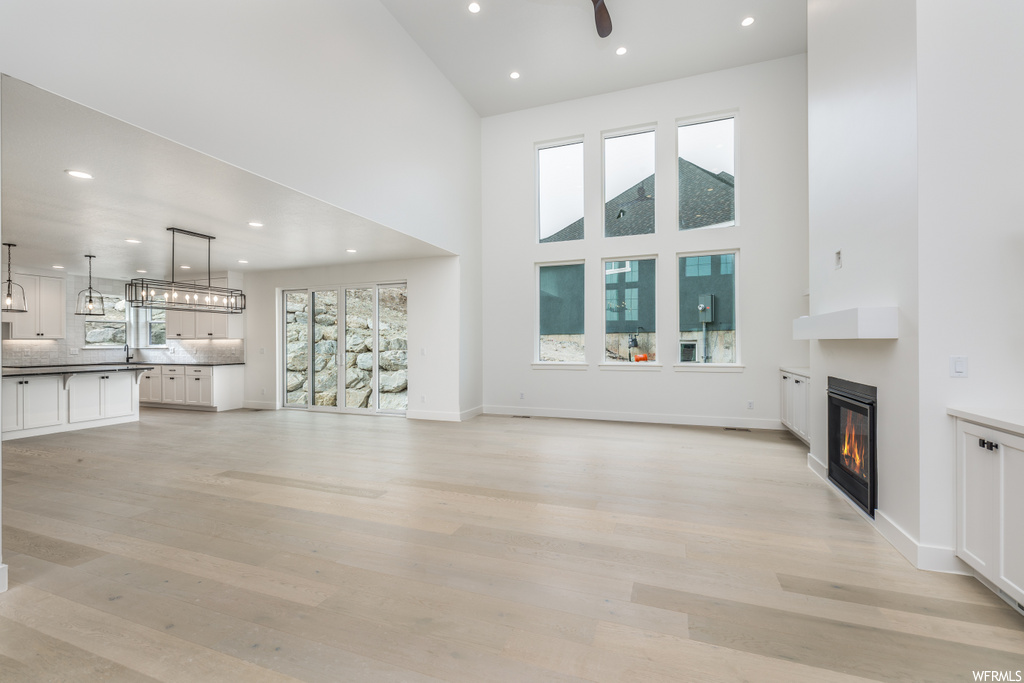living room featuring natural light, a high ceiling, a fireplace, and wood-type flooring