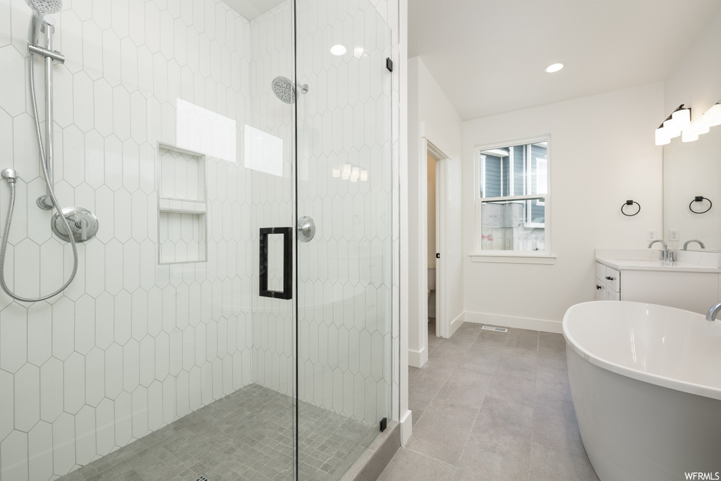 bathroom featuring natural light, tile flooring, separate shower and tub, mirror, and vanity