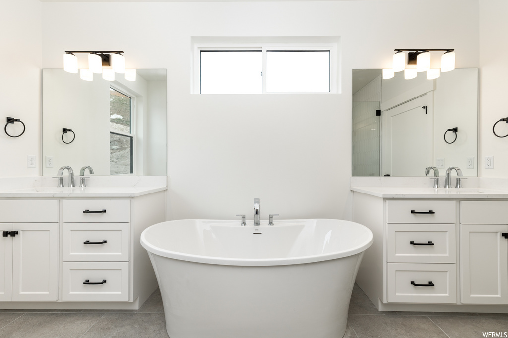 bathroom featuring tile floors, mirror, double vanities, and a bathing tub