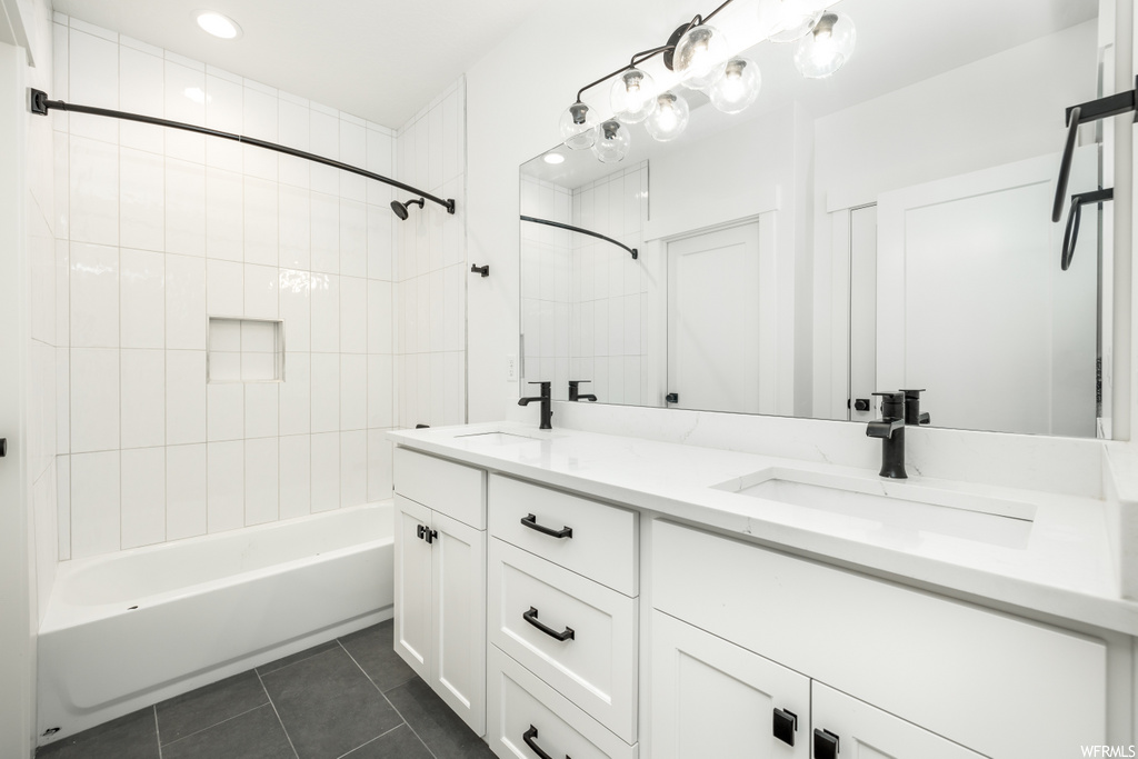 bathroom featuring tile flooring, his and hers vanity, dual mirrors, and washtub / shower combination