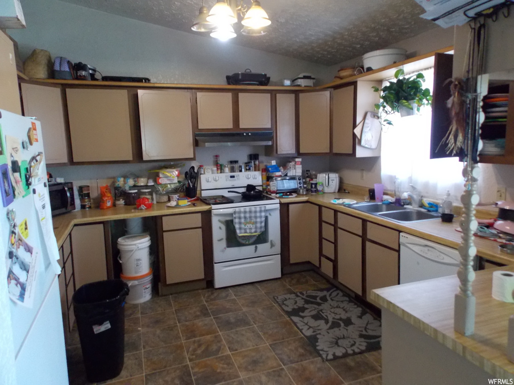 kitchen with microwave, dishwasher, refrigerator, electric range oven, extractor fan, dark flooring, and light countertops