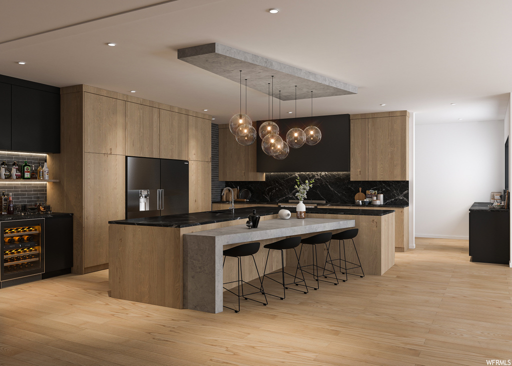 kitchen featuring a kitchen breakfast bar, refrigerator, dark countertops, and light hardwood flooring