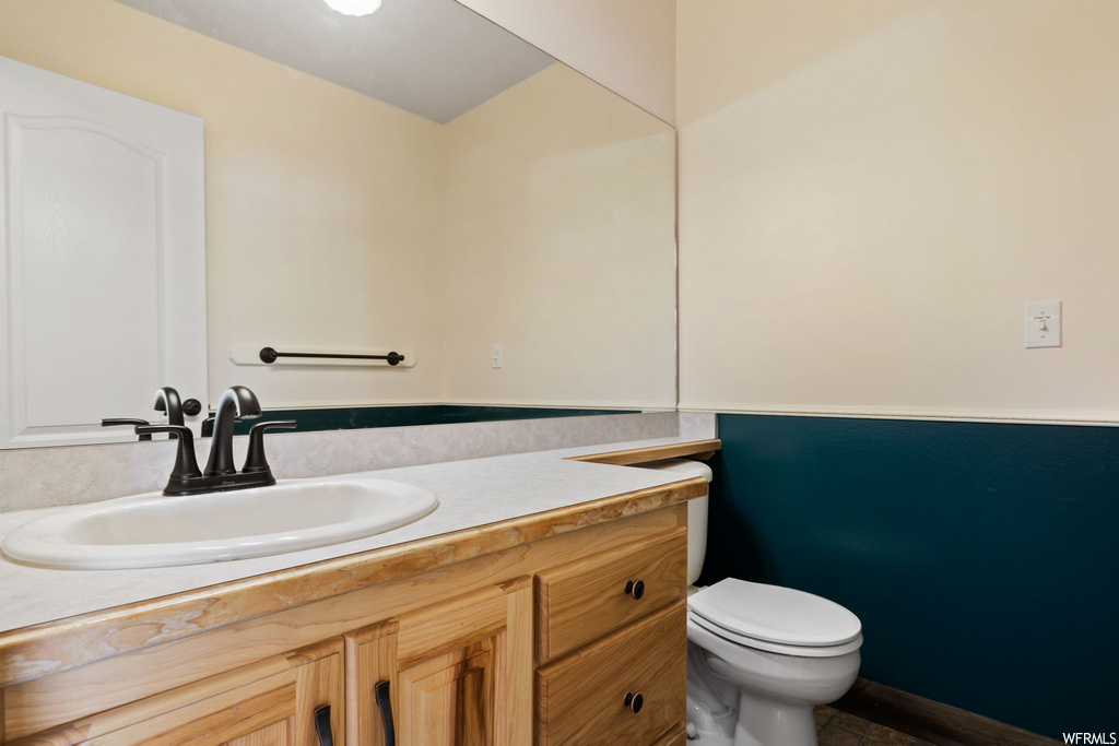half bathroom featuring mirror, vanity, and toilet