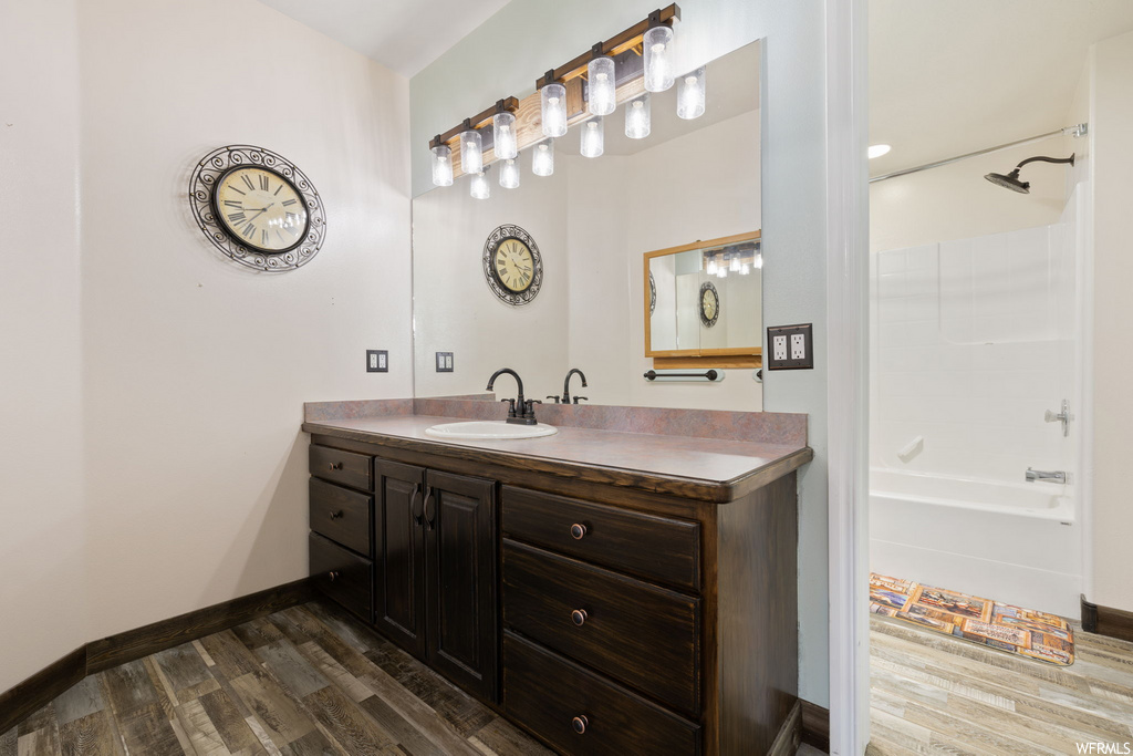 bathroom with hardwood flooring, shower / bathtub combination, mirror, and vanity