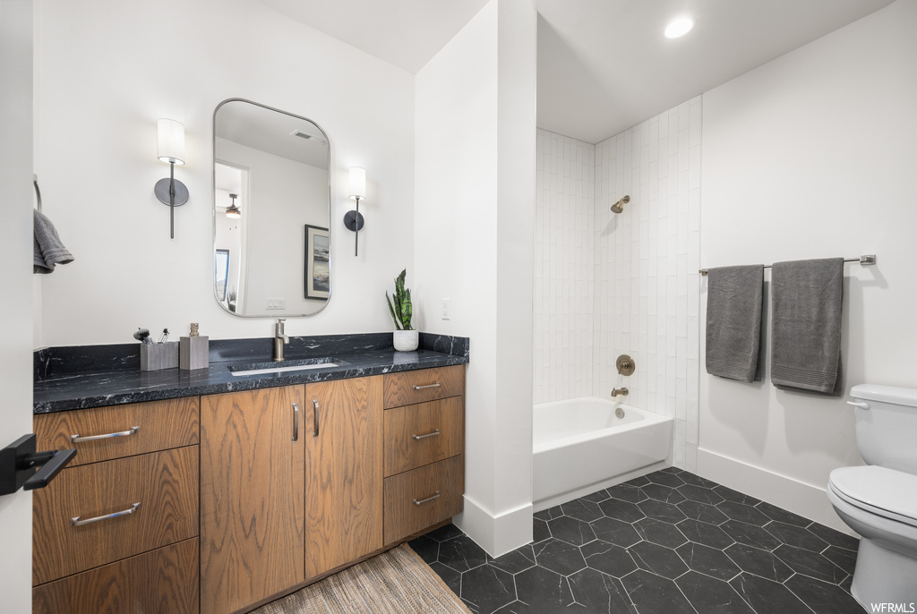 Full bathroom featuring tiled shower / bath combo, oversized vanity, light tile flooring, and mirror