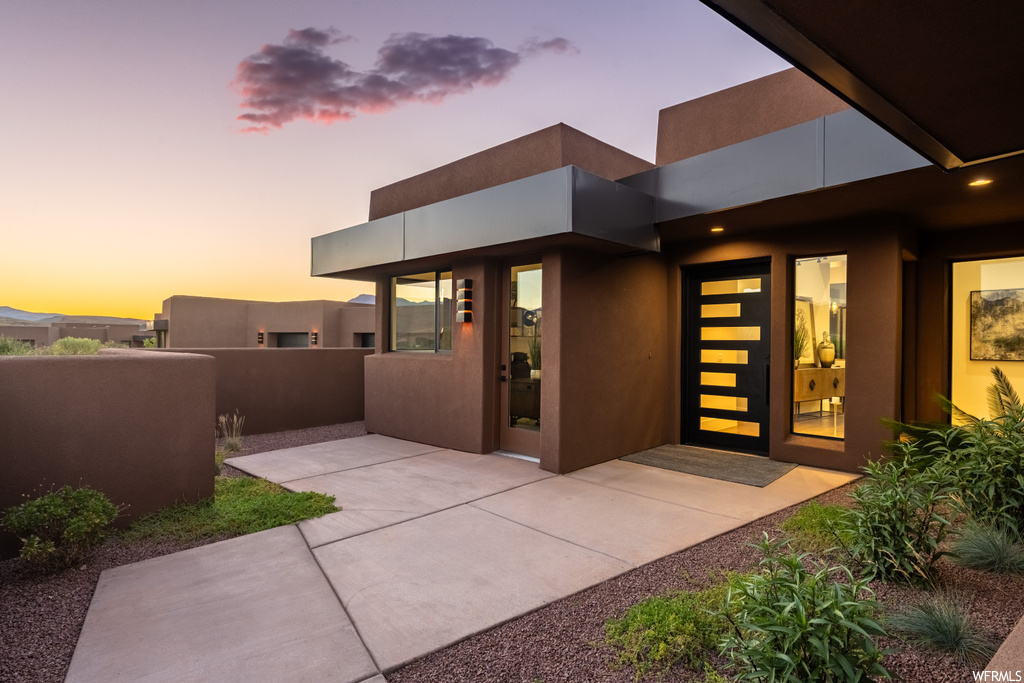 Exterior entry at dusk with a patio
