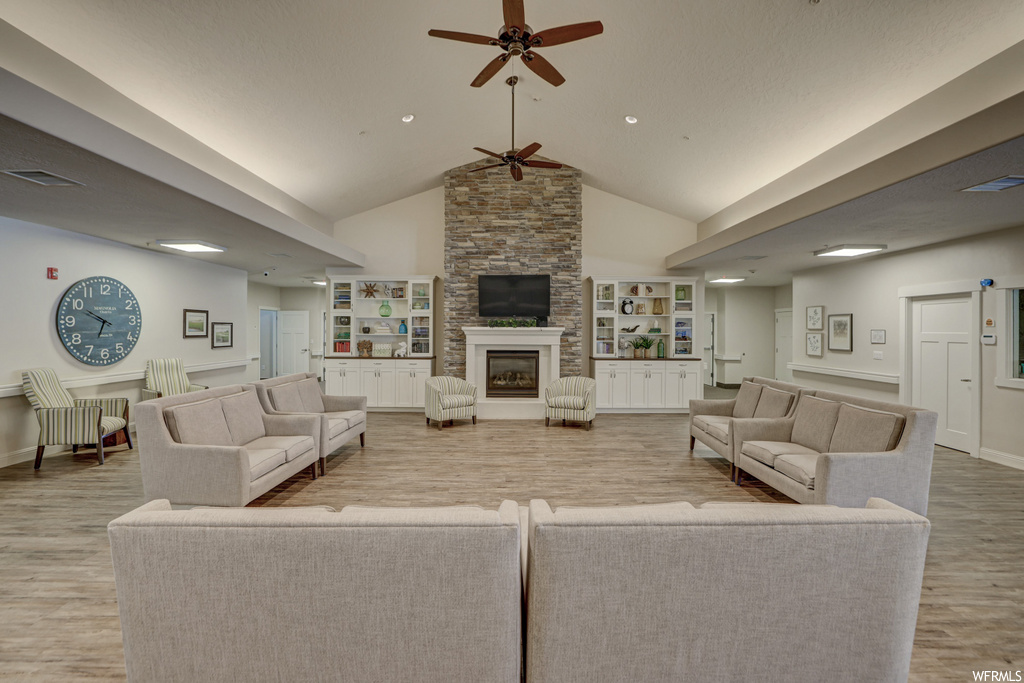 living room with vaulted ceiling, a ceiling fan, a fireplace, hardwood floors, and TV