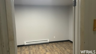 wood floored empty room featuring baseboard radiator