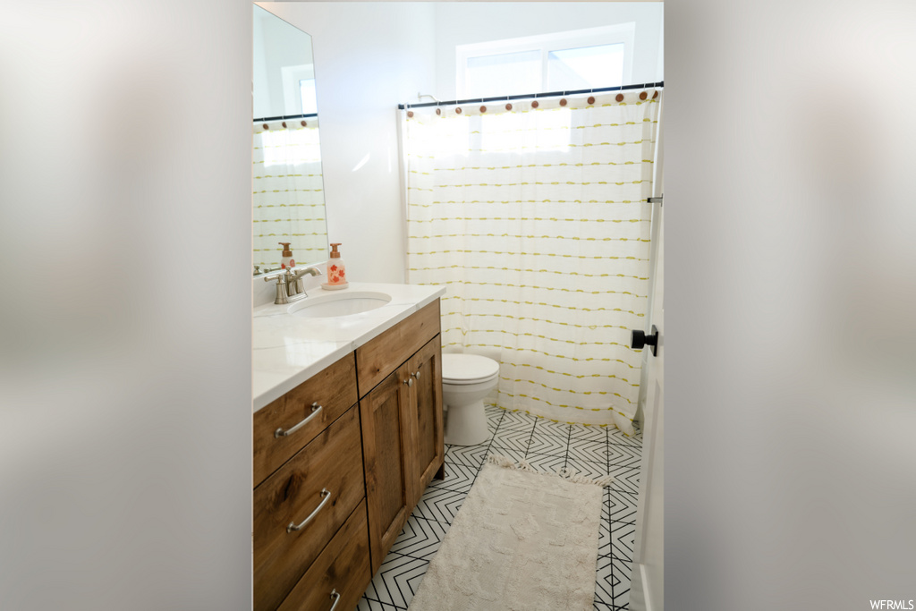 bathroom featuring tile floors, toilet, shower curtain, vanity with extensive cabinet space, and mirror