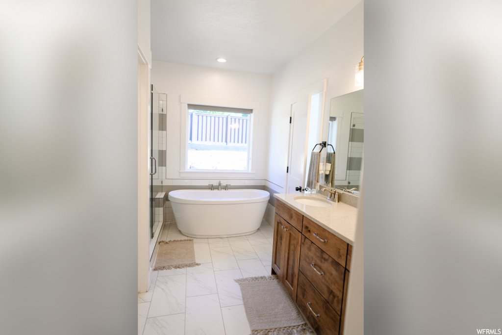 bathroom featuring tile floors, natural light, vanity, a washtub, and mirror