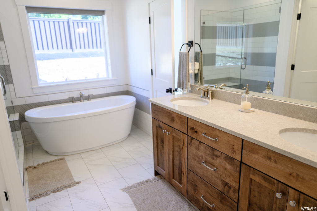 bathroom with natural light, tile flooring, mirror, shower door, a bath, and dual vanity