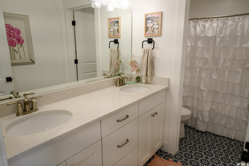 bathroom featuring toilet, multiple mirrors, shower curtain, and dual vanity