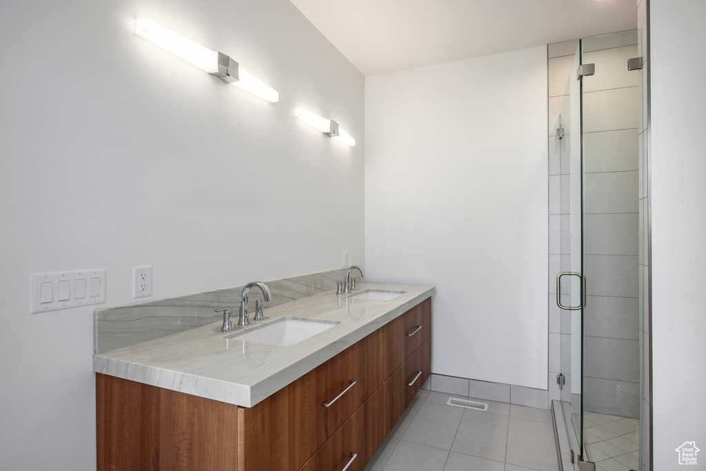 Bathroom featuring walk in shower, tile floors, and dual vanity