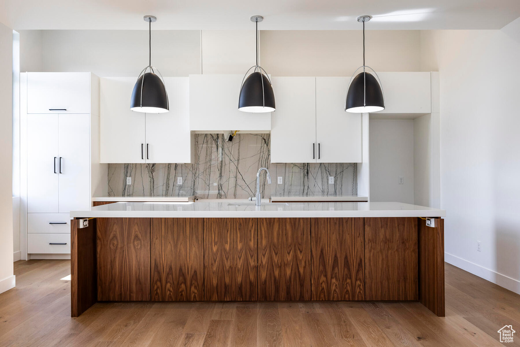 Kitchen featuring backsplash, a kitchen island, light hardwood / wood-style floors, and white cabinets