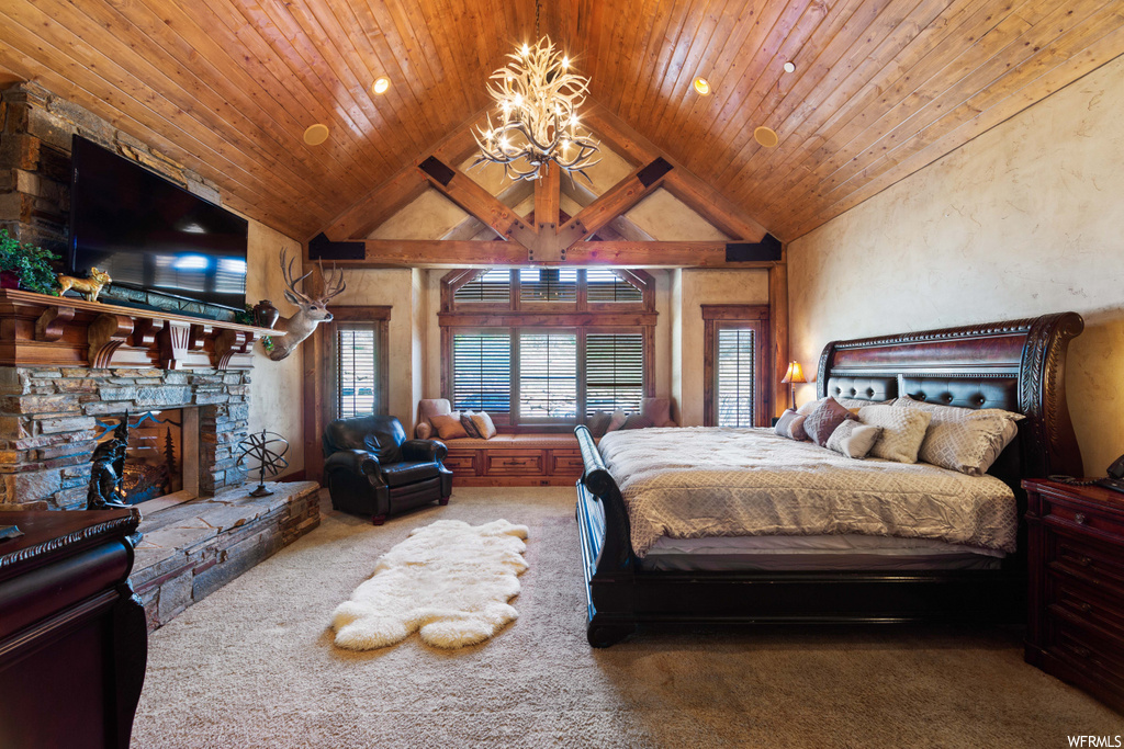 carpeted bedroom featuring vaulted ceiling, a fireplace, a chandelier, and TV