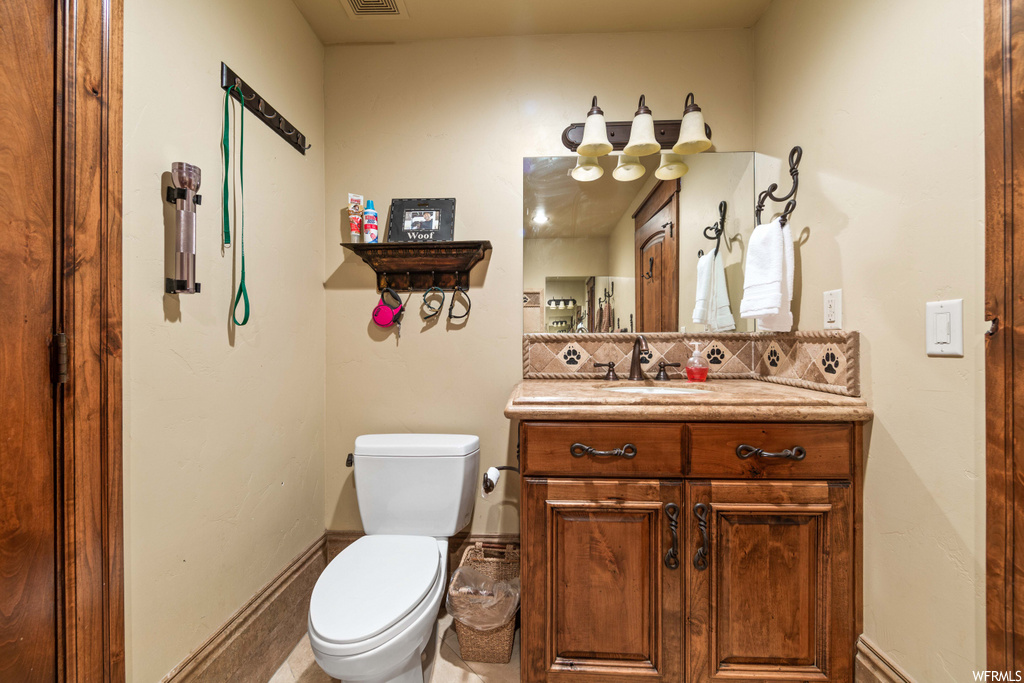 half bath featuring toilet, vanity with extensive cabinet space, and mirror