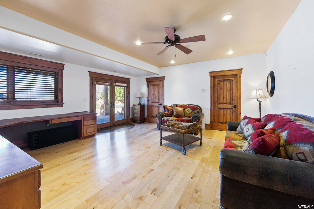 hardwood floored living room featuring natural light and a ceiling fan
