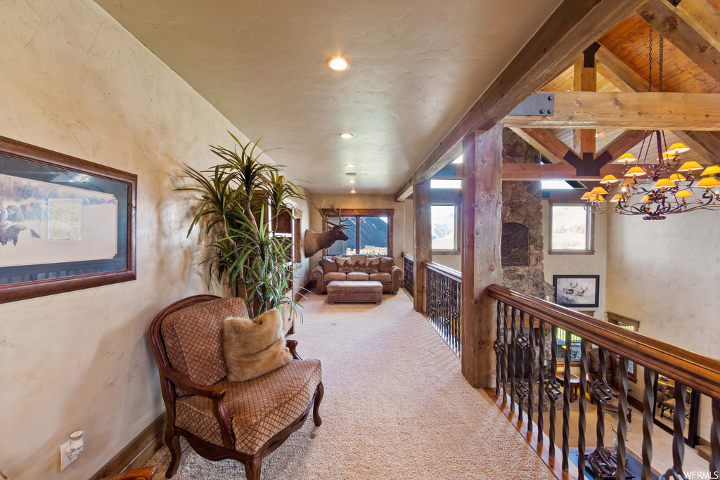 corridor featuring a notable chandelier, wood beam ceiling, plenty of natural light, and carpet