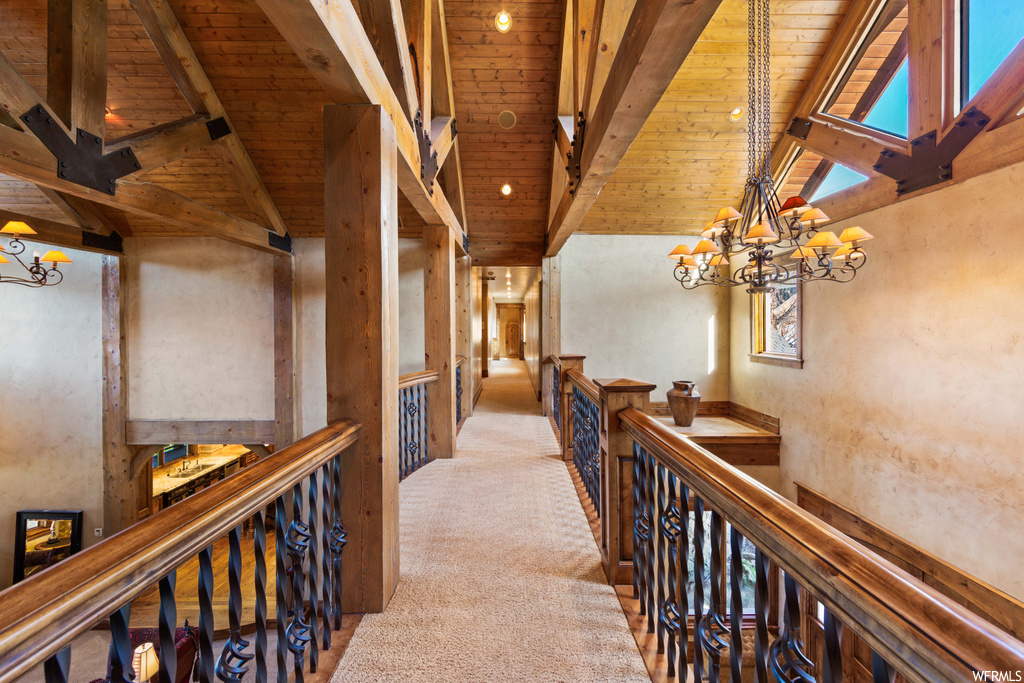 corridor with a notable chandelier, carpet, and wood beam ceiling