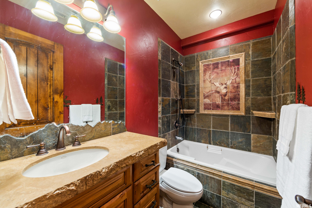 full bathroom featuring toilet, mirror, bathing tub / shower combination, and vanity with extensive cabinet space