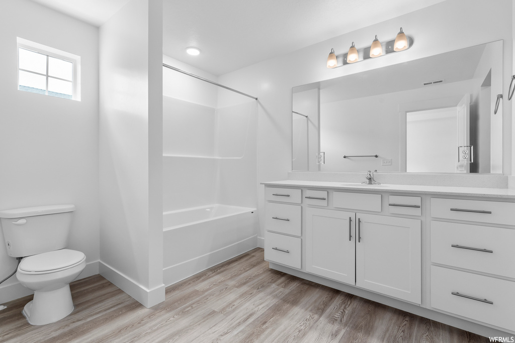 full bathroom featuring hardwood flooring, toilet, shower / tub combination, vanity, and mirror