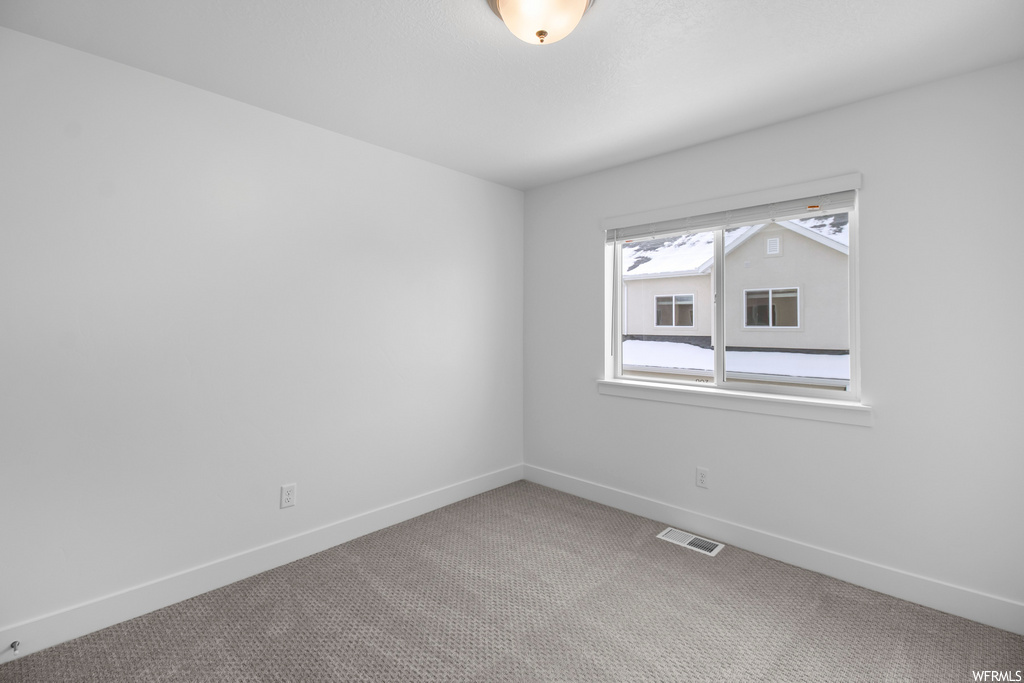 spare room featuring natural light and carpet