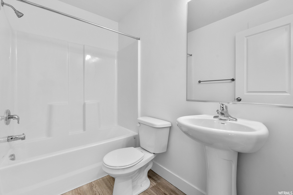 full bathroom with hardwood floors, toilet, sink, shower / bathing tub combination, and mirror