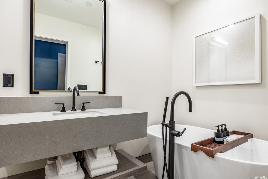 bathroom with a bathing tub, vanity, and mirror