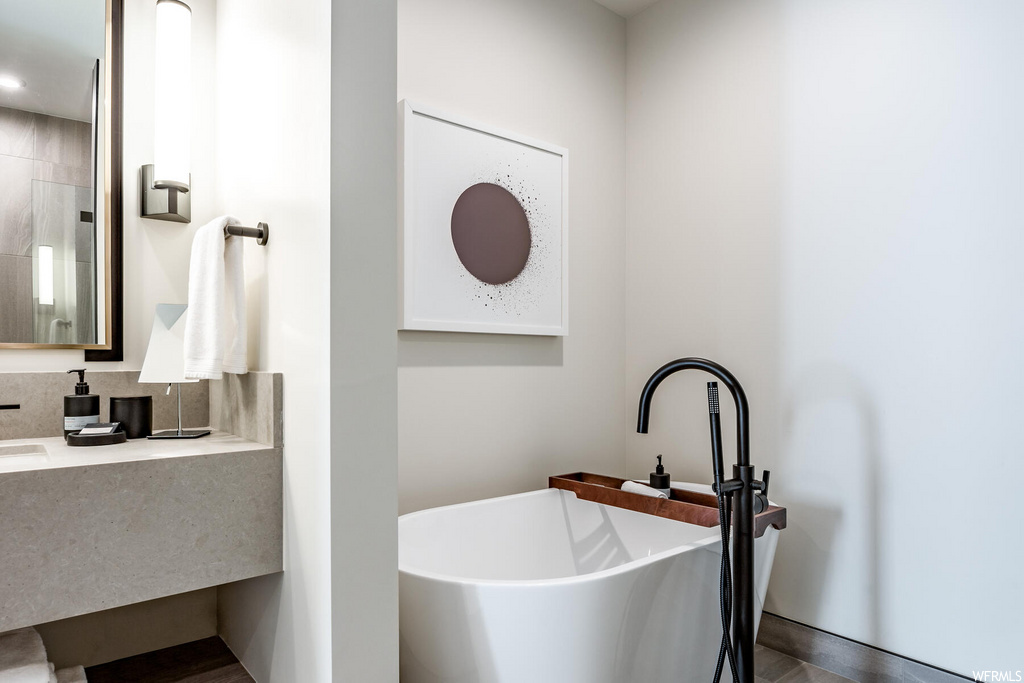 bathroom featuring tile flooring, vanity, mirror, and a tub