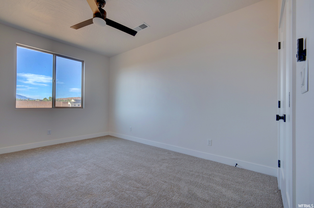 Spare room with natural light, a ceiling fan, and carpet