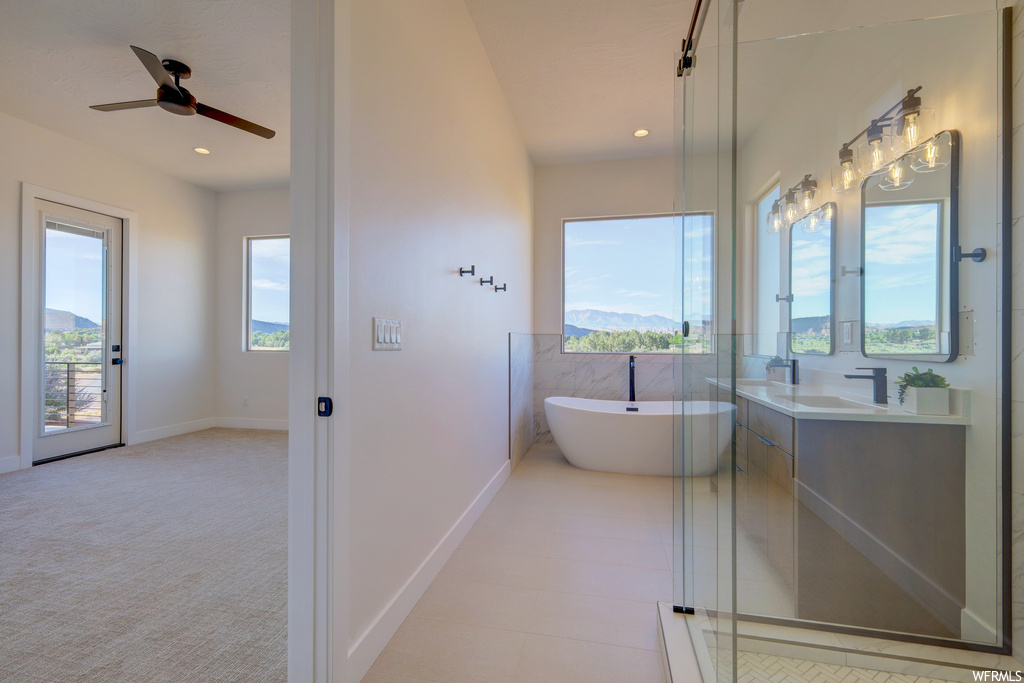 Bathroom featuring natural light, a ceiling fan, mirror, shower with separate bathtub, and vanity