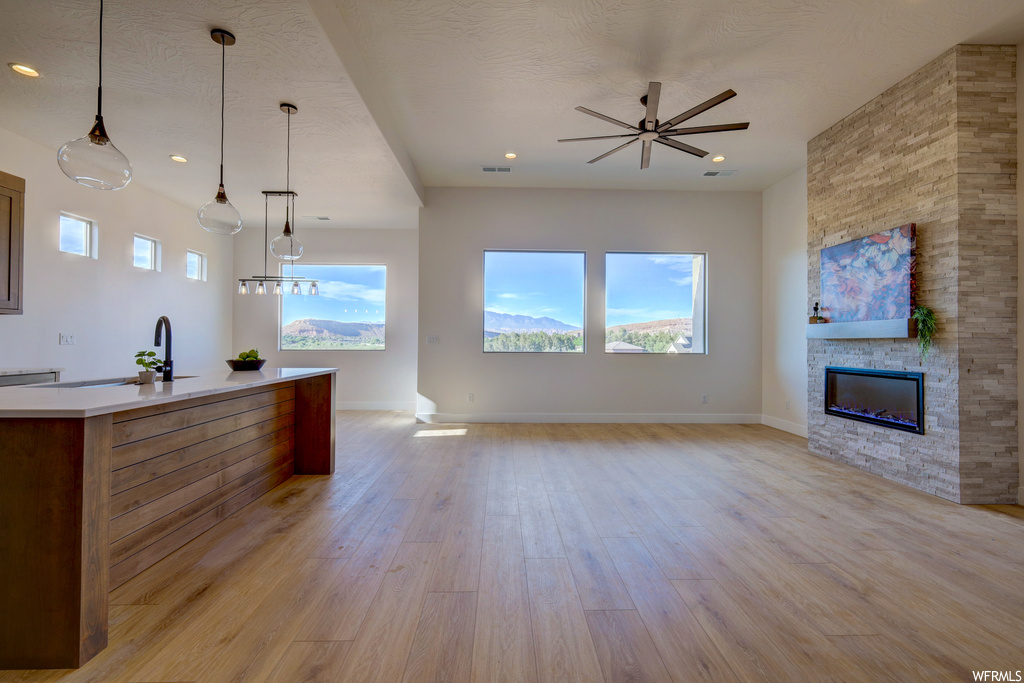 Kitchen featuring natural light, a fireplace, light countertops, light hardwood flooring, and pendant lighting