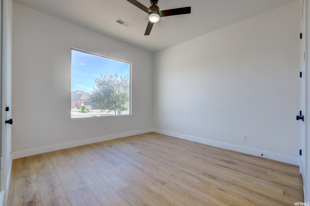 Spare room featuring hardwood floors, natural light, and a ceiling fan