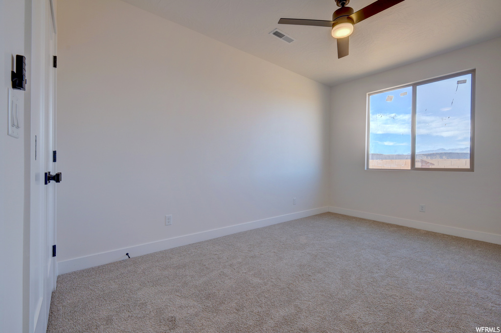 Carpeted spare room featuring a ceiling fan