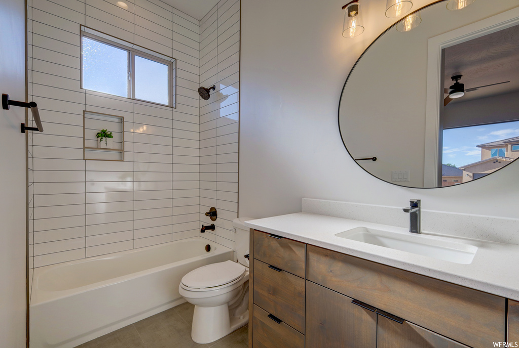 Full bathroom with tile flooring, plenty of natural light, toilet, mirror, washtub / shower combination, and vanity