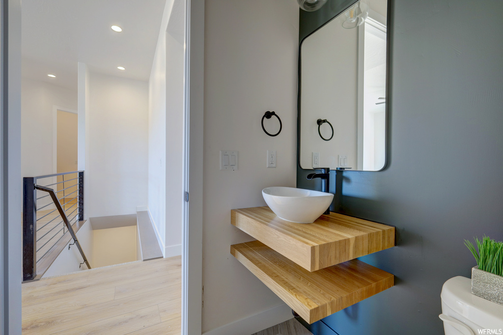 Half bath featuring wood-type flooring, mirror, toilet, and vanity