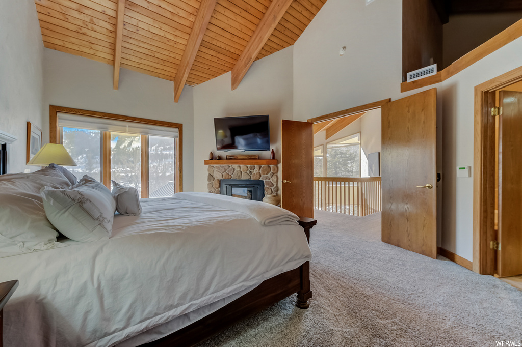bedroom with a fireplace, natural light, carpet, vaulted ceiling with beams, a high ceiling, and TV