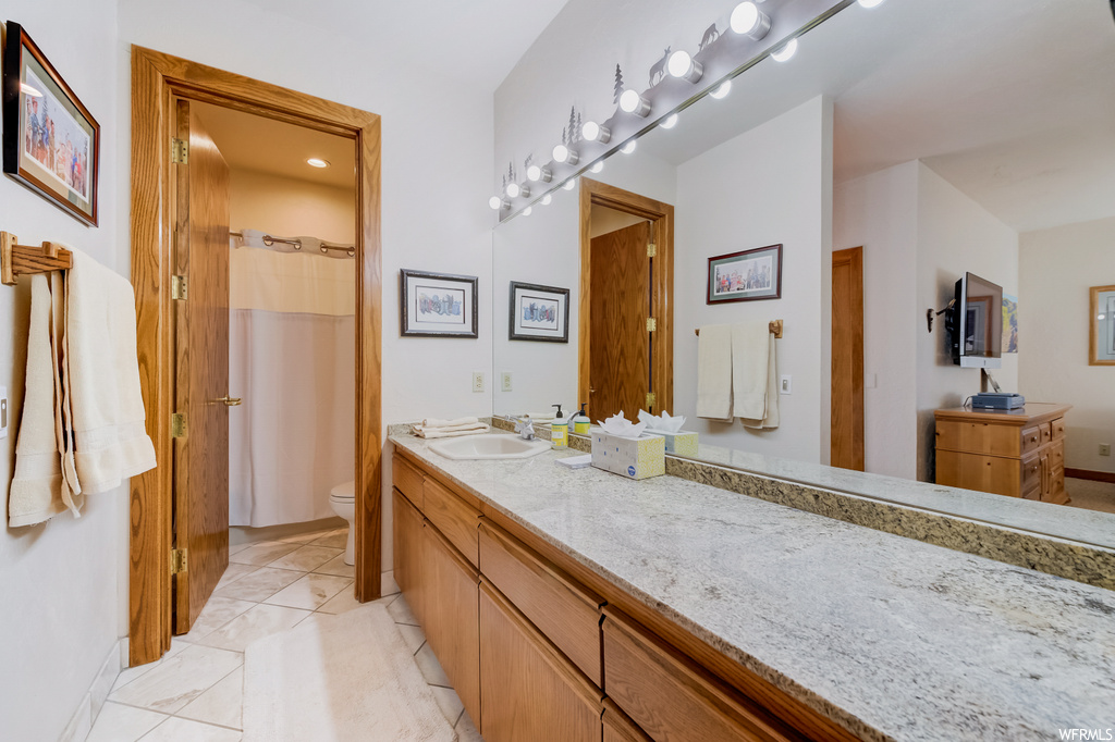 bathroom with tile flooring, dual bowl vanity, shower curtain, toilet, and dual mirrors
