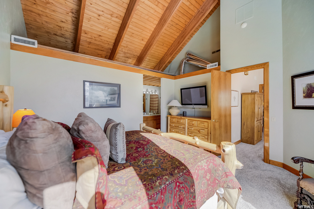 carpeted bedroom featuring lofted ceiling with beams and TV