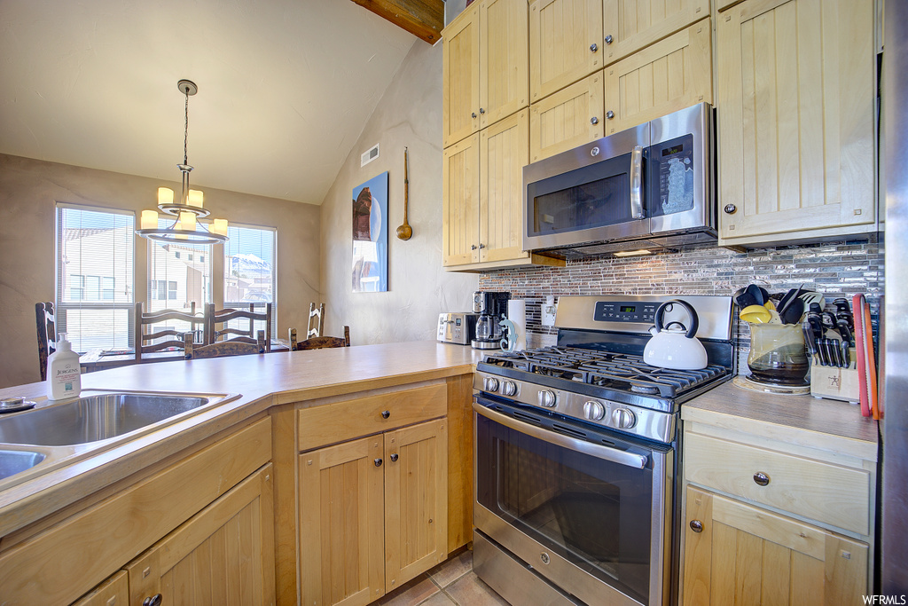 kitchen featuring tile flooring, gas range oven, microwave, and light countertops