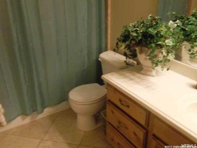 bathroom with tile flooring, toilet, multiple mirrors, shower curtain, and large vanity