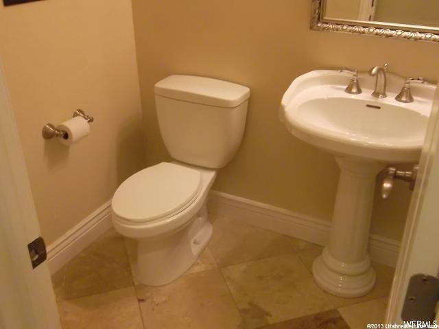 half bath featuring tile floors, toilet, sink, and mirror
