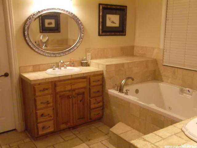 bathroom with tile flooring, vanity, mirror, and a bathing tub