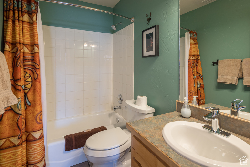 Full bathroom featuring shower / bath combo with shower curtain, toilet, and vanity