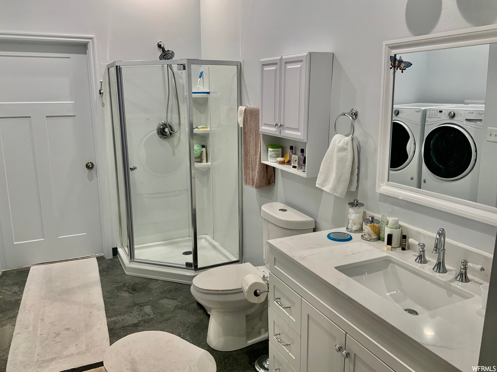 full bathroom with tile flooring, washer / dryer, toilet, large vanity, enclosed shower, and mirror