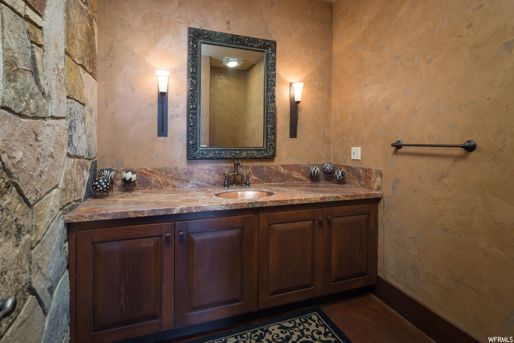 bathroom with hardwood flooring, large vanity, and mirror