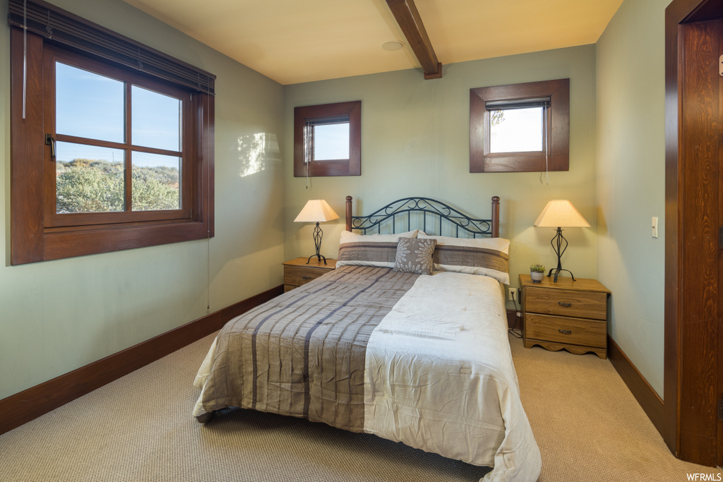 bedroom featuring natural light, wood beam ceiling, and carpet