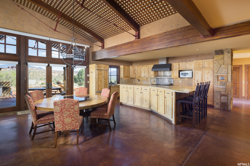 dining area with natural light, a breakfast bar, a chandelier, wood beam ceiling, and microwave