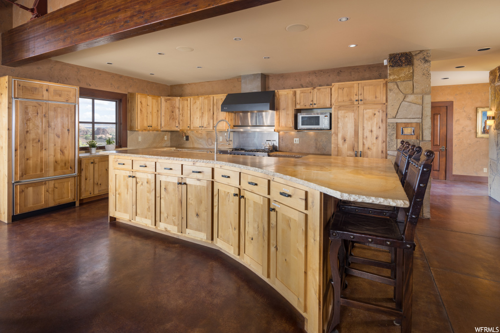 kitchen featuring natural light, microwave, dark floors, light countertops, and brown cabinets