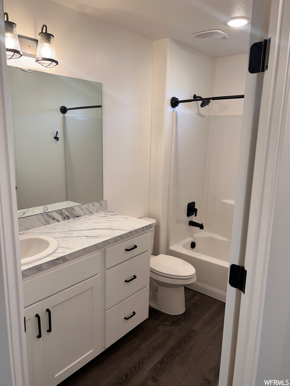 Full bathroom featuring vanity, mirror, tub / shower combination, and dark hardwood floors